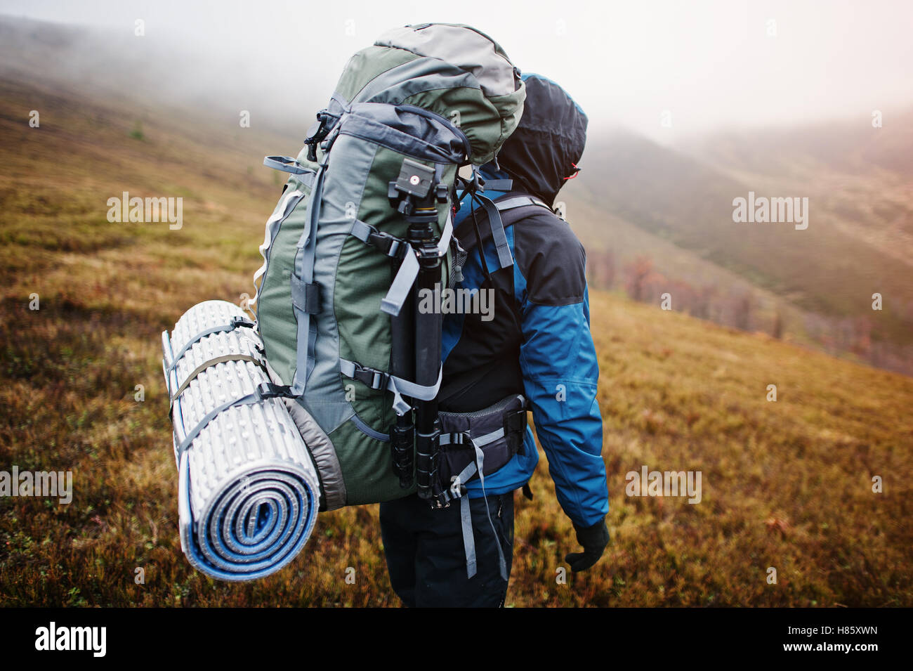 Vista cercana de espalda mochila turística mats y trípode, vistiendo sobre  turismo azul chaqueta con capucha y de pie sobre la montaña Fotografía de  stock - Alamy