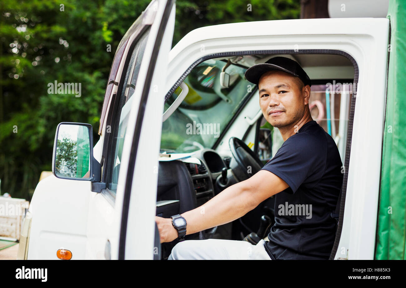 Un hombre joven sentado en un camión en una granja comercial en Japón. Foto de stock