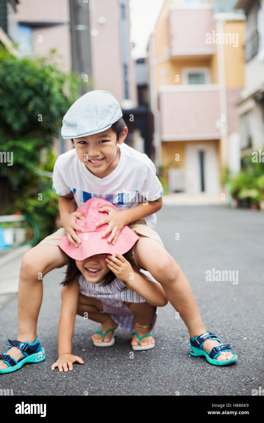 Casa de familia. Dos niños, un niño y una niña jugando al aire libre. Foto de stock