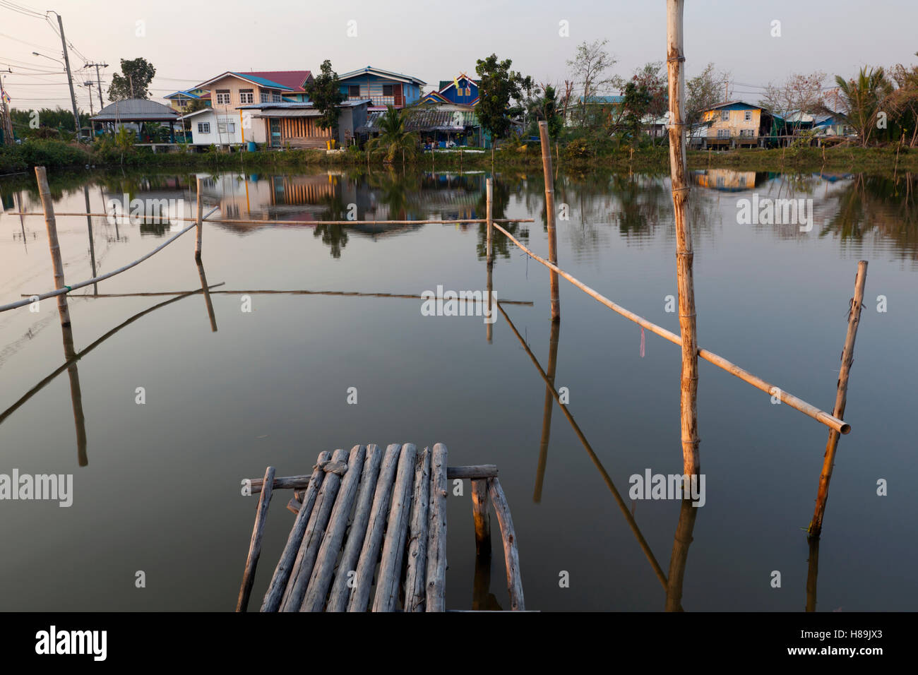 Grupo de casas entre los estanques de camarones en la vasta región de cría de camarones de la Provincia Samut Prakan en Tailandia. Foto de stock