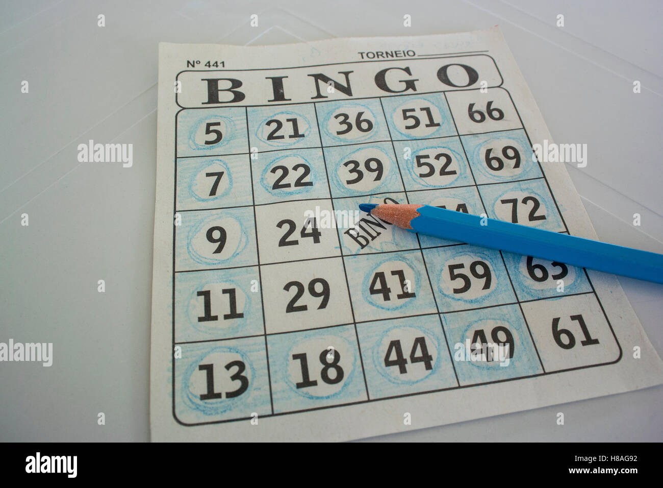 Una tarjeta de bingo conun lápiz azul sobre una tabla blanca Foto de stock