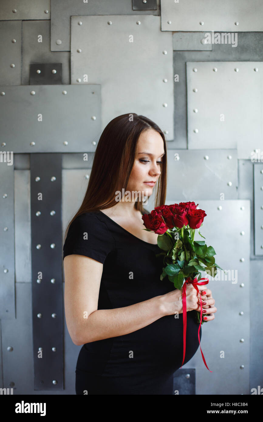 Hermosa joven embarazada en vestido negro con rosas rojas Fotografía de  stock - Alamy
