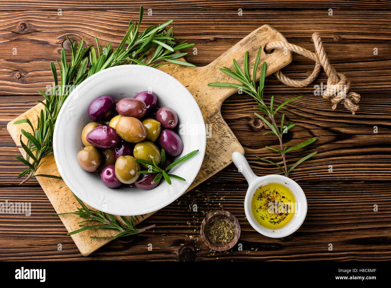 Ingredientes de comida italiana, romero, aceitunas, aceite de oliva sobre fondo de madera Foto de stock