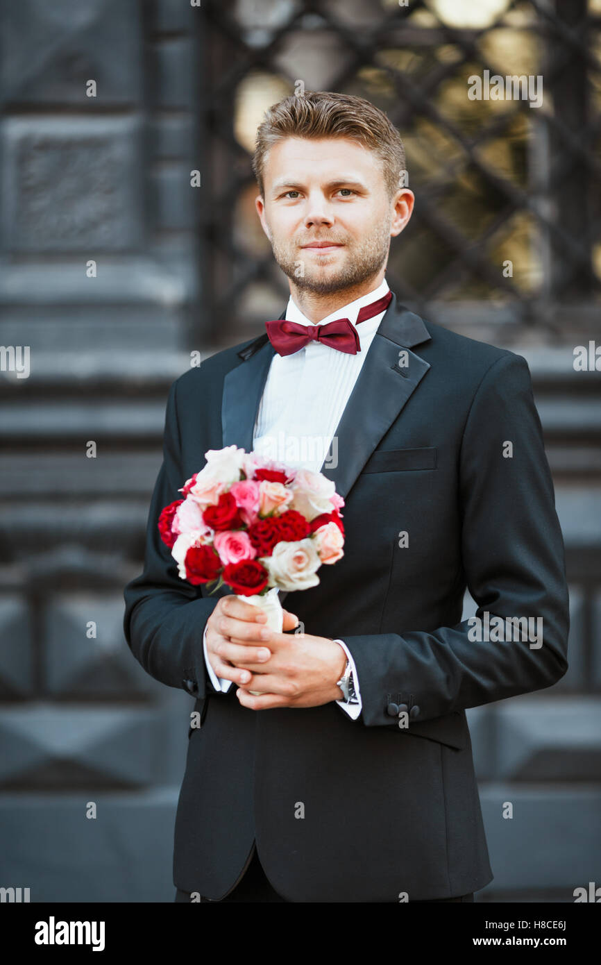 Sesión de fotos de boda. Esposo de pie con bouquet. Hombre vestido con  camisa blanca, chaqueta negra y arco-nudo. Piscina Fotografía de stock -  Alamy