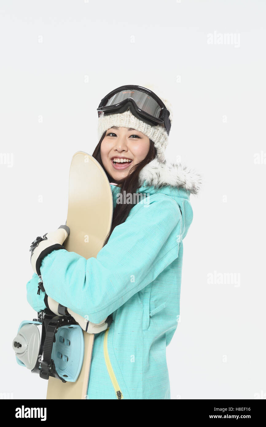 Jovencita japonesa desgaste desgaste snowboard sobre fondo blanco. Foto de stock
