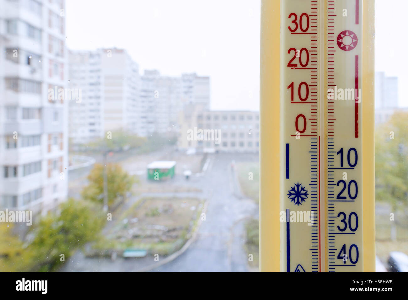 Un termómetro, fijo fuera de la ventana, muestra que es de cero grados centígrados, mientras que el exterior está caliente en el interior de la sala Foto de stock