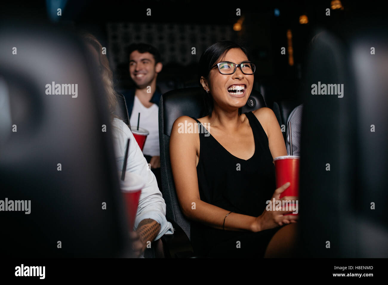 Foto de joven mujer sentada en el cine multiplex viendo la película y riendo. Foto de stock