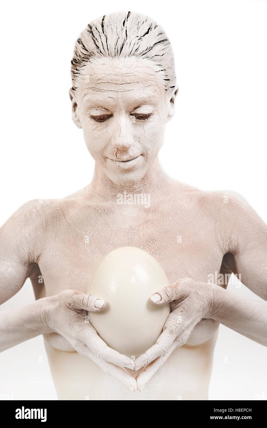 Mujer cubierta en barro de arcilla la celebración de huevo de avestruz Foto de stock