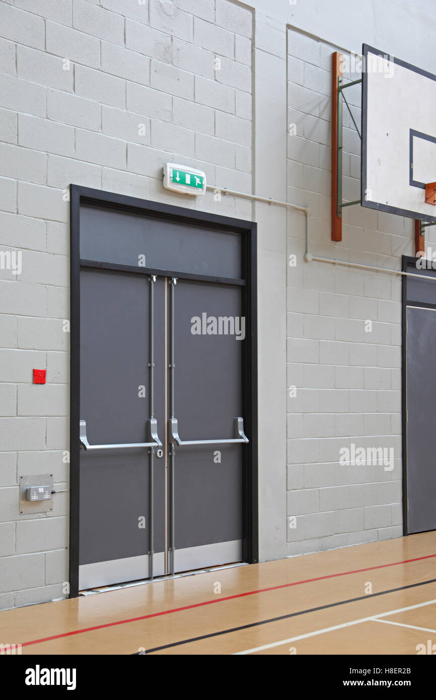 Puerta de escape en caso de incendio en la sala de deportes de una moderna escuela de Londres. Muestra la barra de empuje y sistema de tornillo de pánico Foto de stock