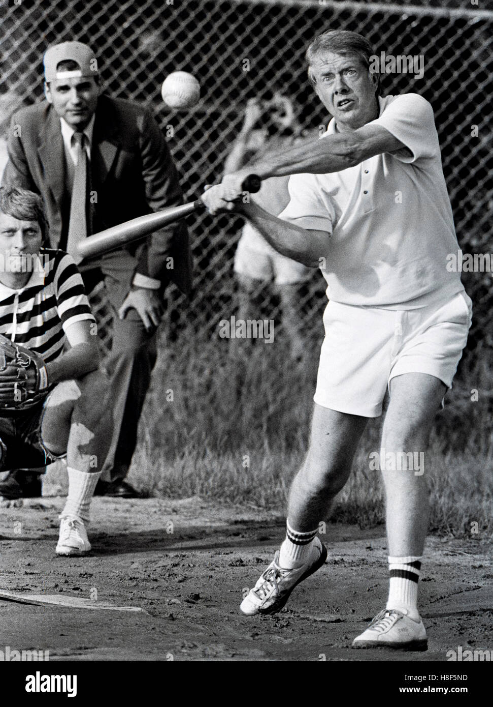 El presidente Jimmy Carter al bate durante el juego de softball en llanuras High School en su ciudad natal de Plains, Georgia. El árbitro en el fondo es defensor del consumidor Ralph Nader y el catcher James Wooten es reportero del New York Times. Foto de stock