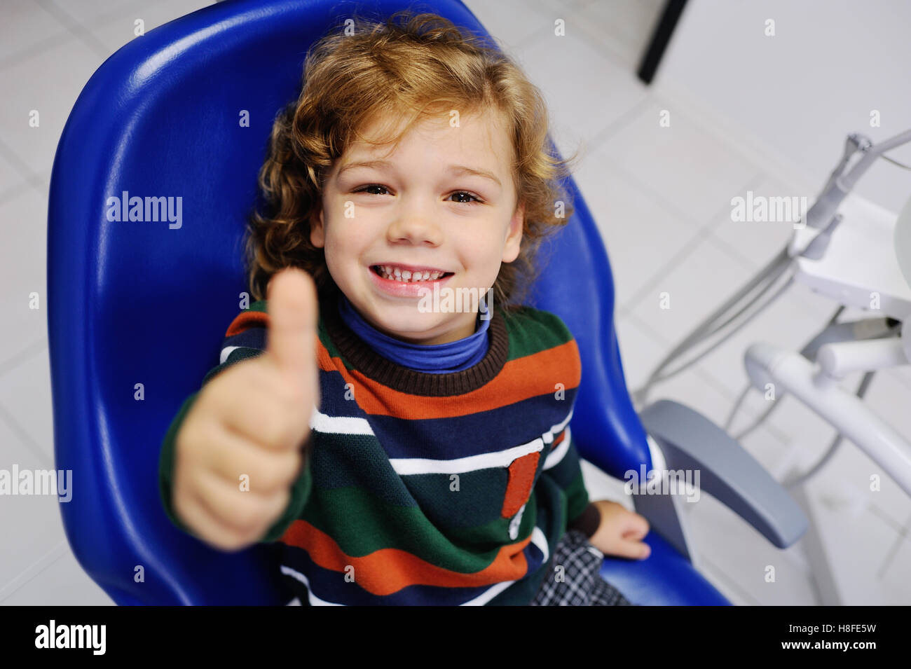 Lindo bebé en un suéter a rayas en la recepción por el dentista Foto de stock