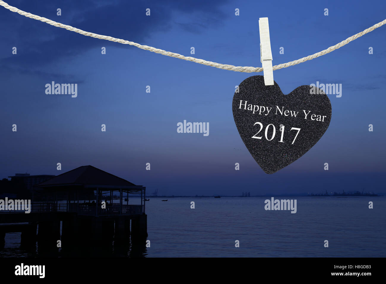 Corazón negro colgado en cuerda de cáñamo en Sunrise tienen antecedentes y feliz año nuevo 2017 de texto. Foto de stock