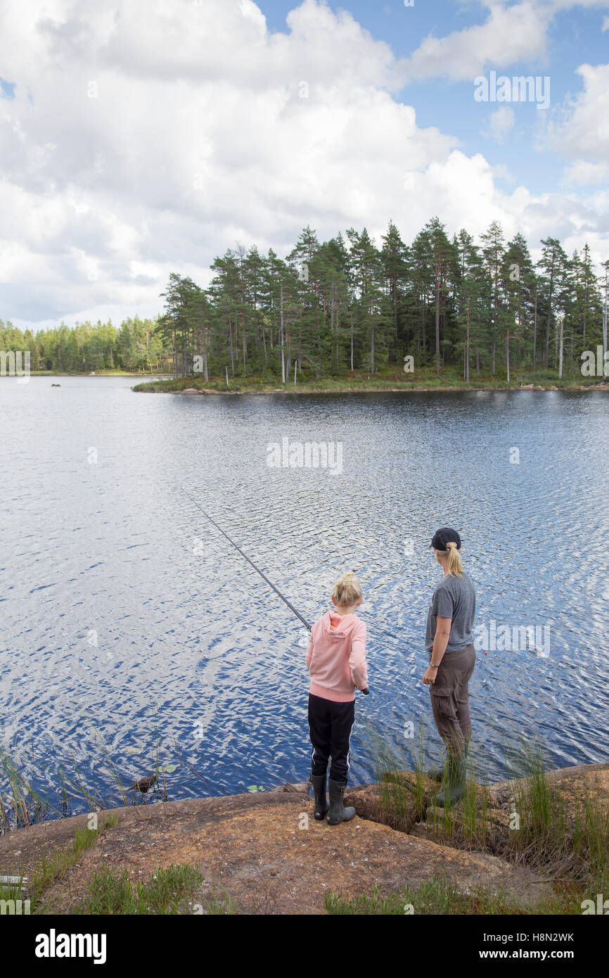 Mujer madura y chica (12-13) la pesca en el lago Foto de stock