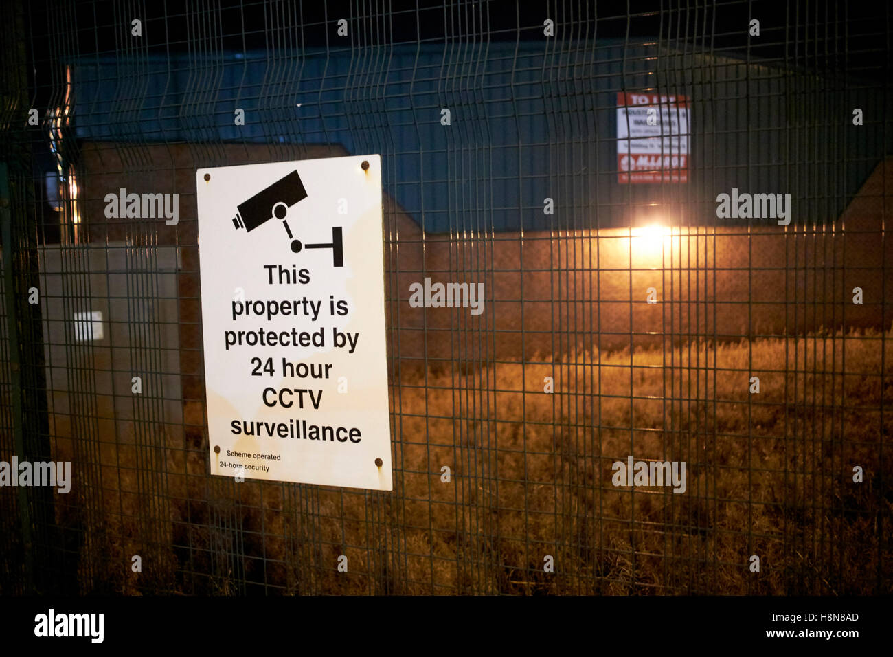 Edificio industrial en la noche con una señal de advertencia de CCTV de 24hr en Newtownabbey Reino Unido Irlanda del Norte Foto de stock