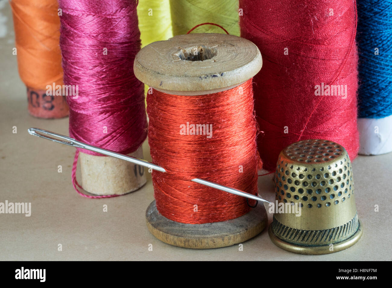 Hilos de coser con aguja y dedal Foto de stock