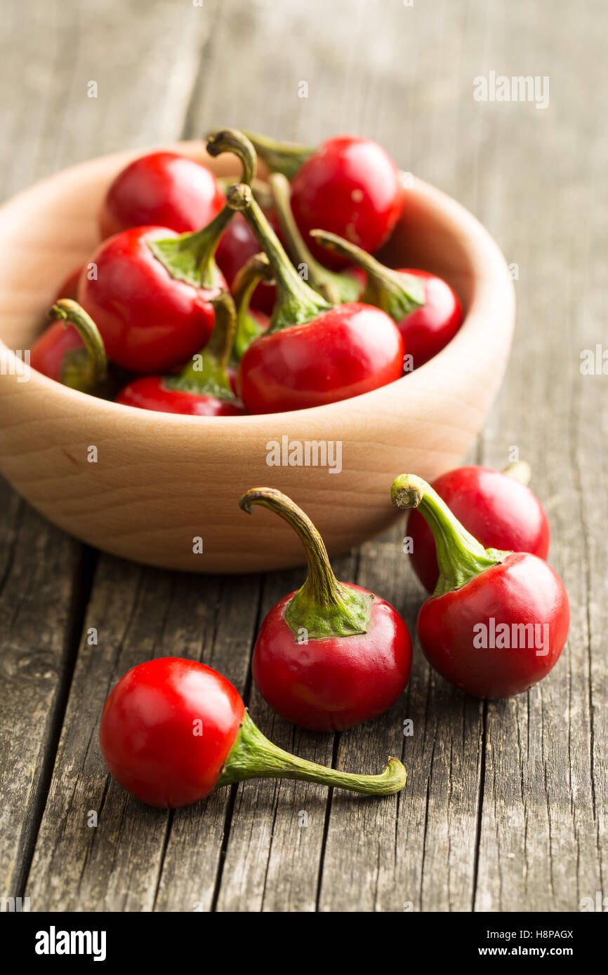 Pimientos rojos en el recipiente sobre la mesa de madera. Foto de stock