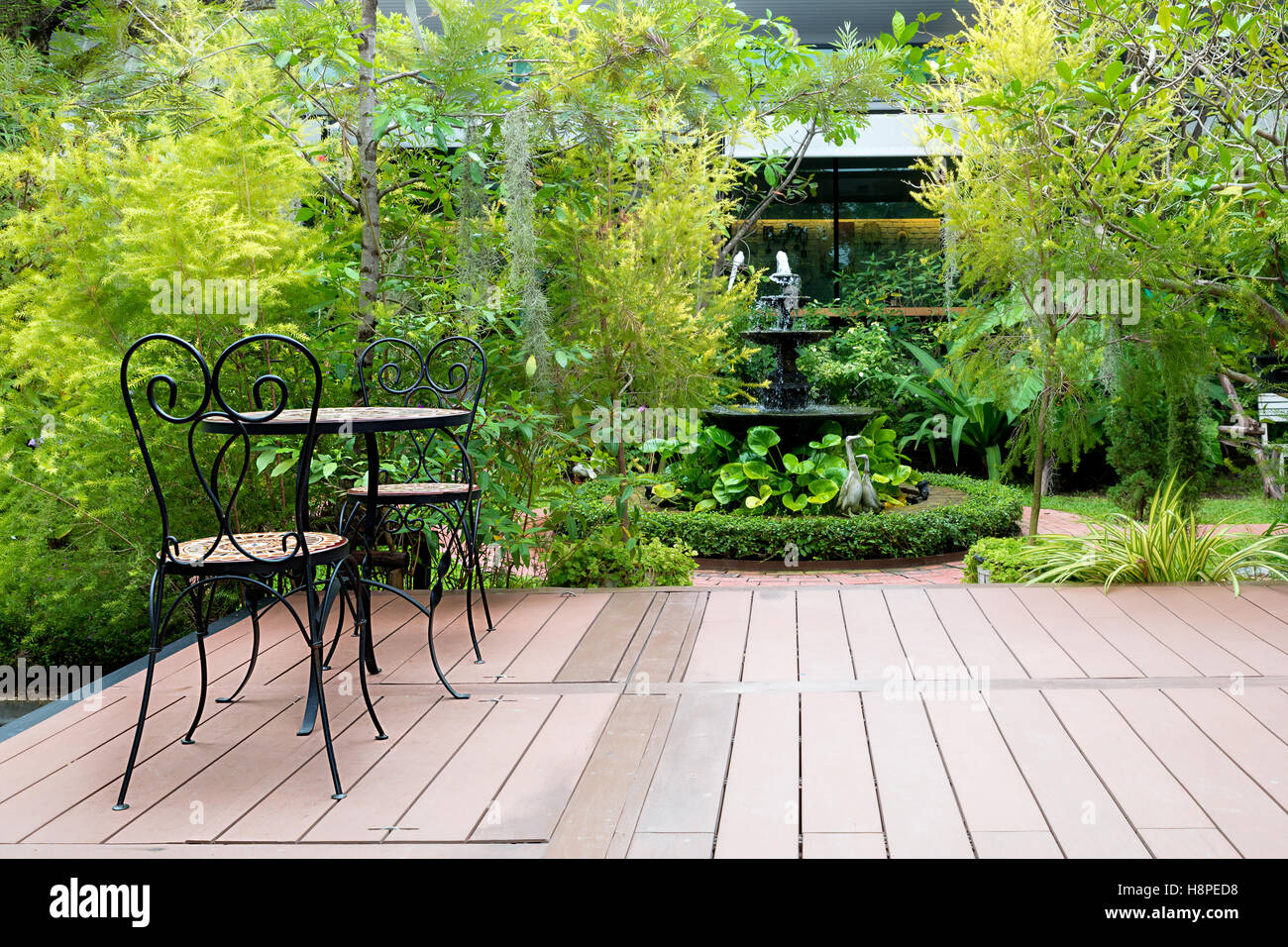 Silla de madera negra en el verde patio jardín con una fuente en casa. El jardín exterior. Foto de stock