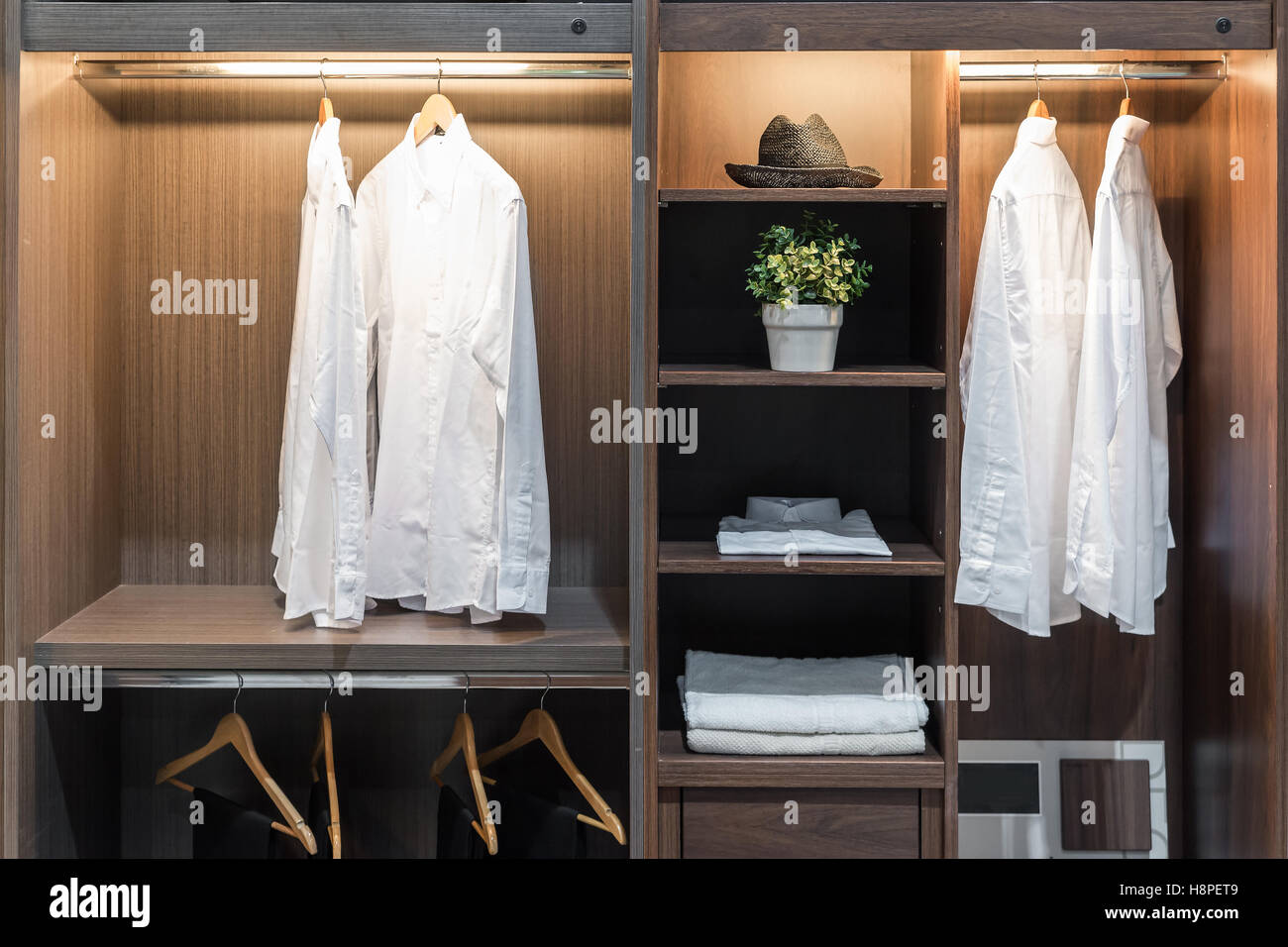 Interior moderno armario con camisa, pantalones, gorro y toalla en el estante. Foto de stock