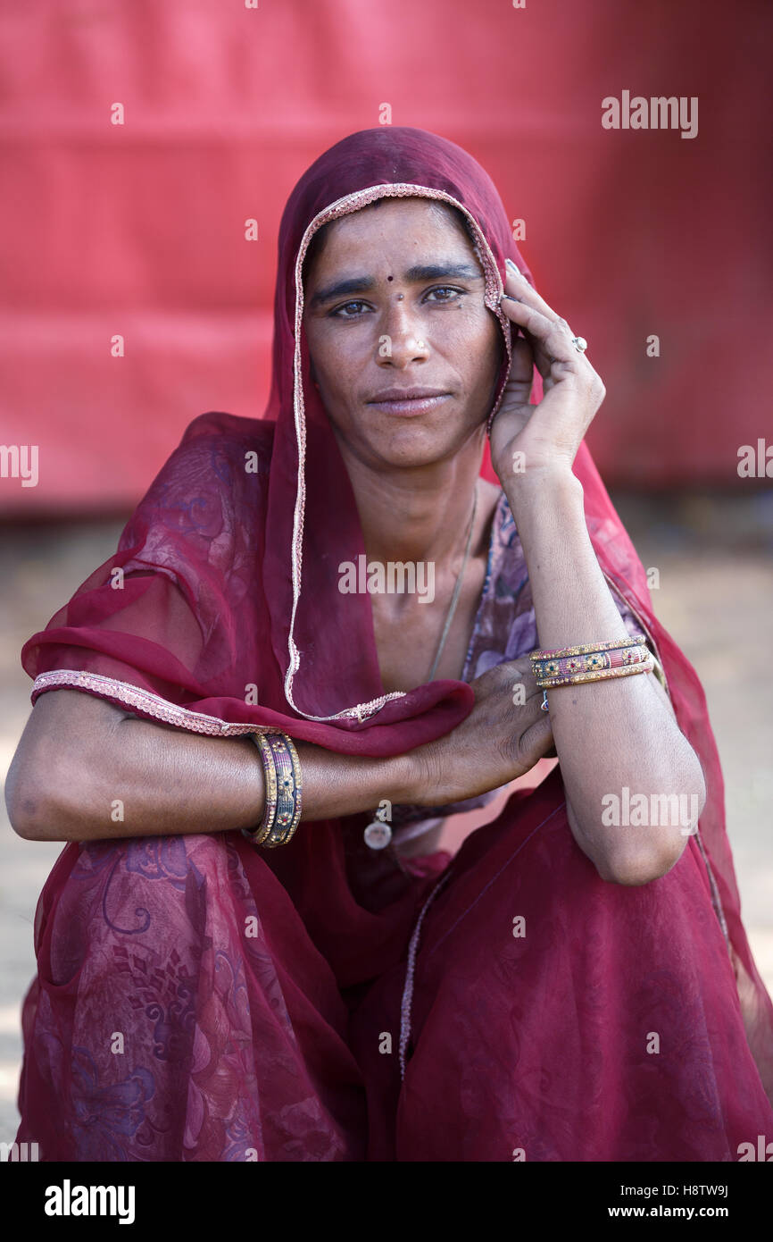 Mujer vestida de india tradicional bufanda y Sari, se sienta delante de la carpa roja y mira a la cámara Foto de stock
