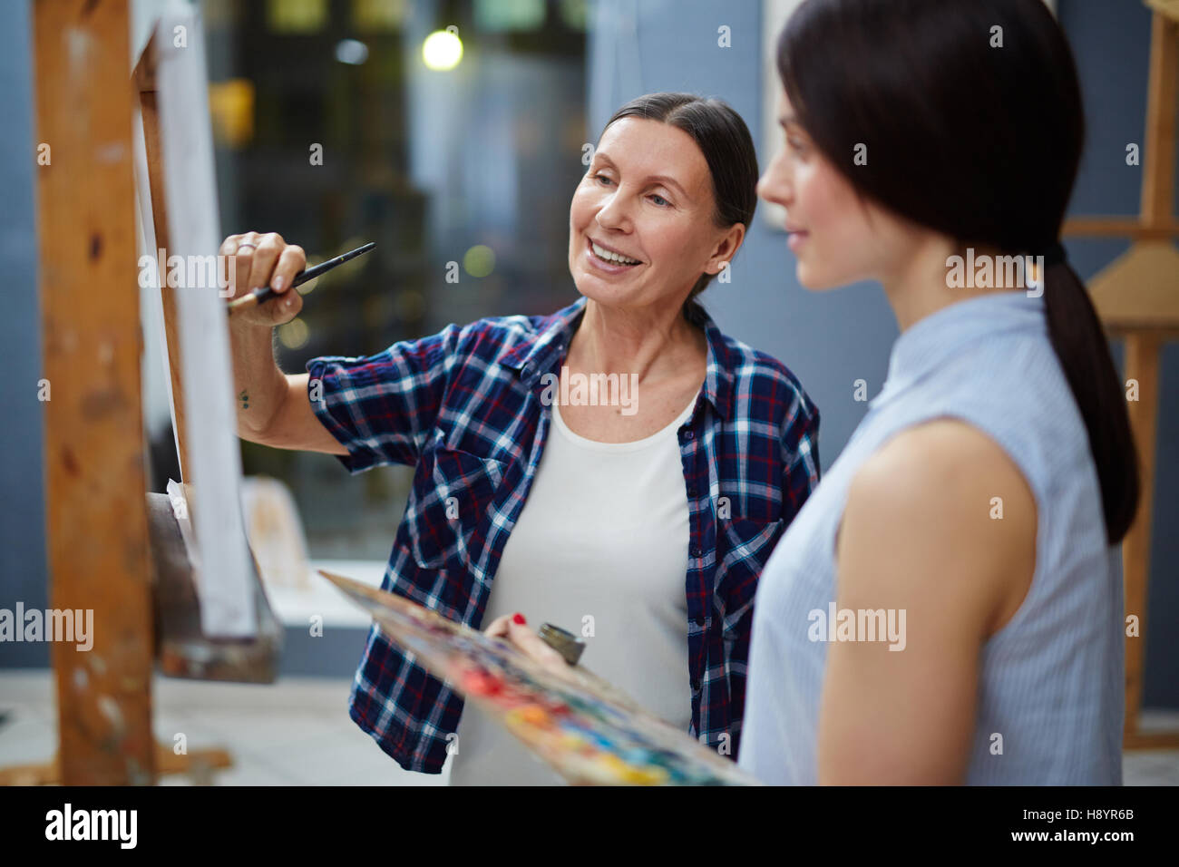 Experimentado profesor de pintura muestra su estudiante cómo hacerlo profesionalmente Foto de stock