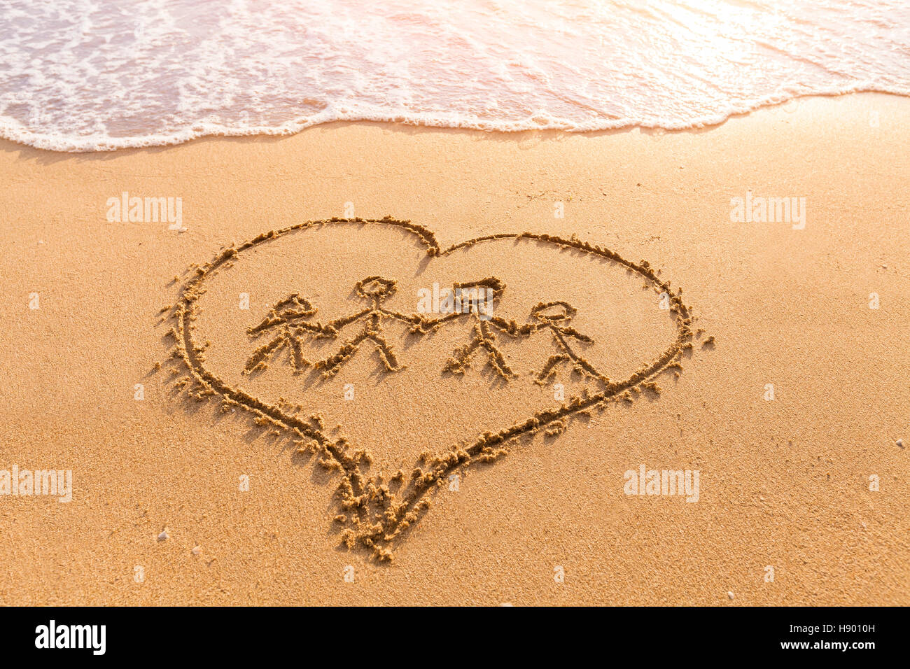 Forma de las manos de la familia dentro de un corazón dibujado en la arena, padres e hijos, el amor, juntos, las vacaciones de verano Foto de stock