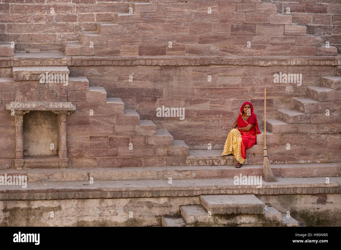 Mujer de Sari descansando sobre los pasos a Toorji Jhalara Ka, la paso bien, Jodhpur, Rajasthan, India Foto de stock