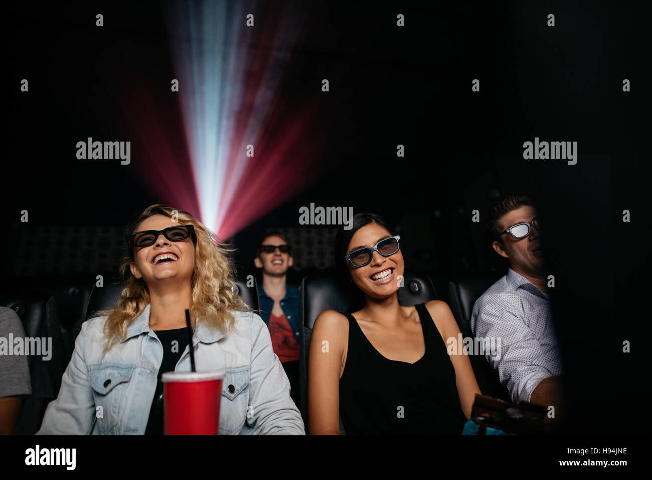 Las mujeres jóvenes viendo películas en 3D en el teatro. Personas en teatro con gafas 3d. Foto de stock