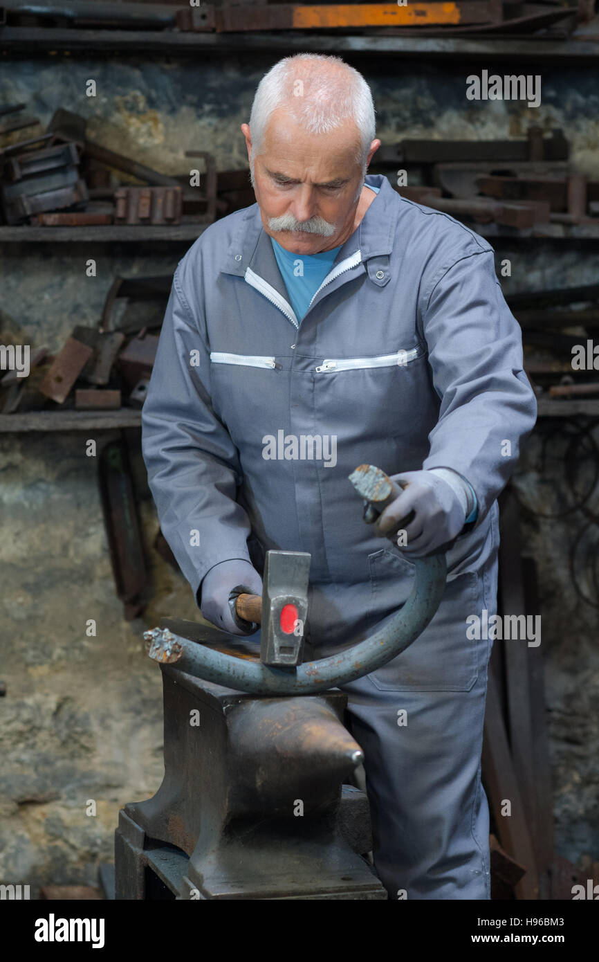 Herrero forja un hierro candente en la forja. martillo de forja de  estructuras metálicas en un yunque de hierro fundido al aire libre en la  naturaleza Fotografía de stock - Alamy