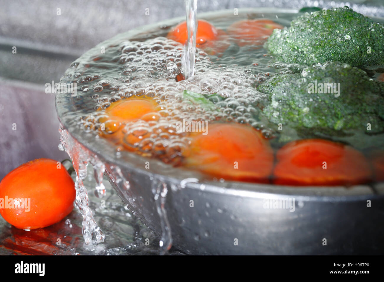 Lavar verdura fresca en el fregadero Foto de stock