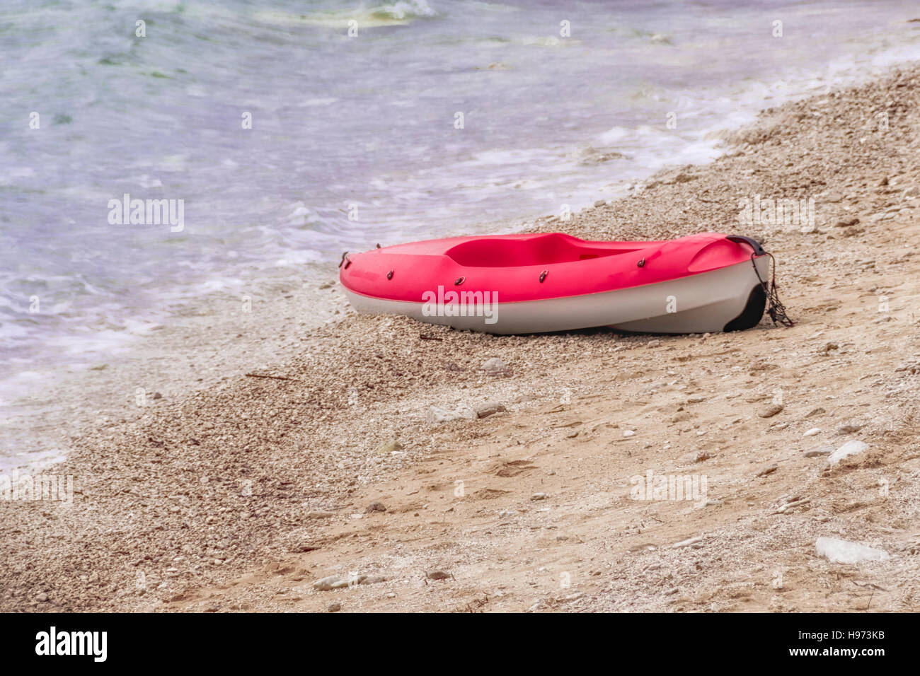 Canoa de plástico rojo y blanco en la playa de arena, copyspace, nadie Foto de stock