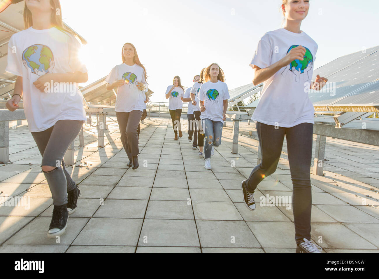 Grupo de adolescentes ambientalistas que corre a lo largo de paneles solares Foto de stock