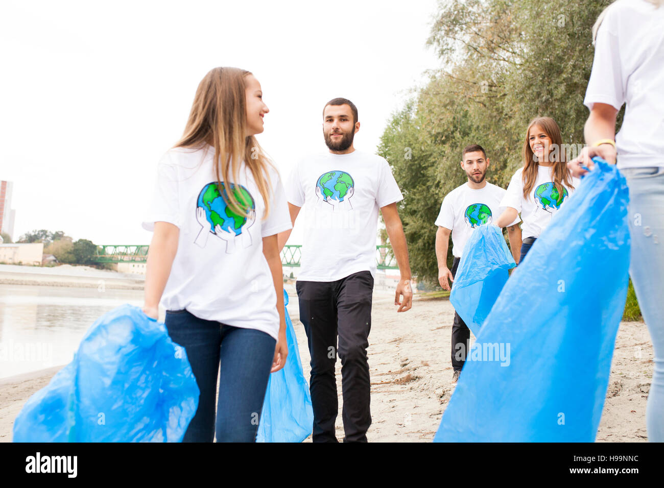 Voluntarios adolescentes haciendo limpieza de basura en la orilla Foto de stock