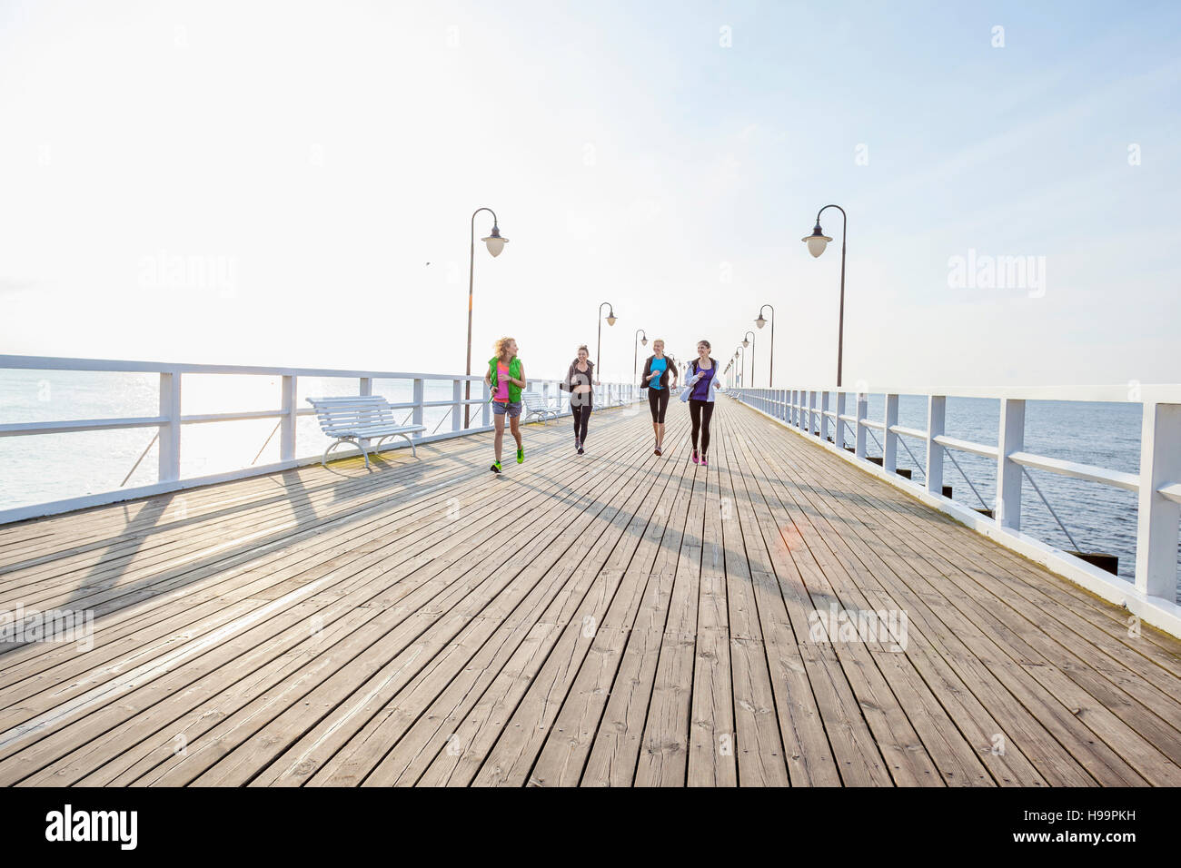 Grupo de mujeres en ropa deportiva corriendo en jetty Foto de stock