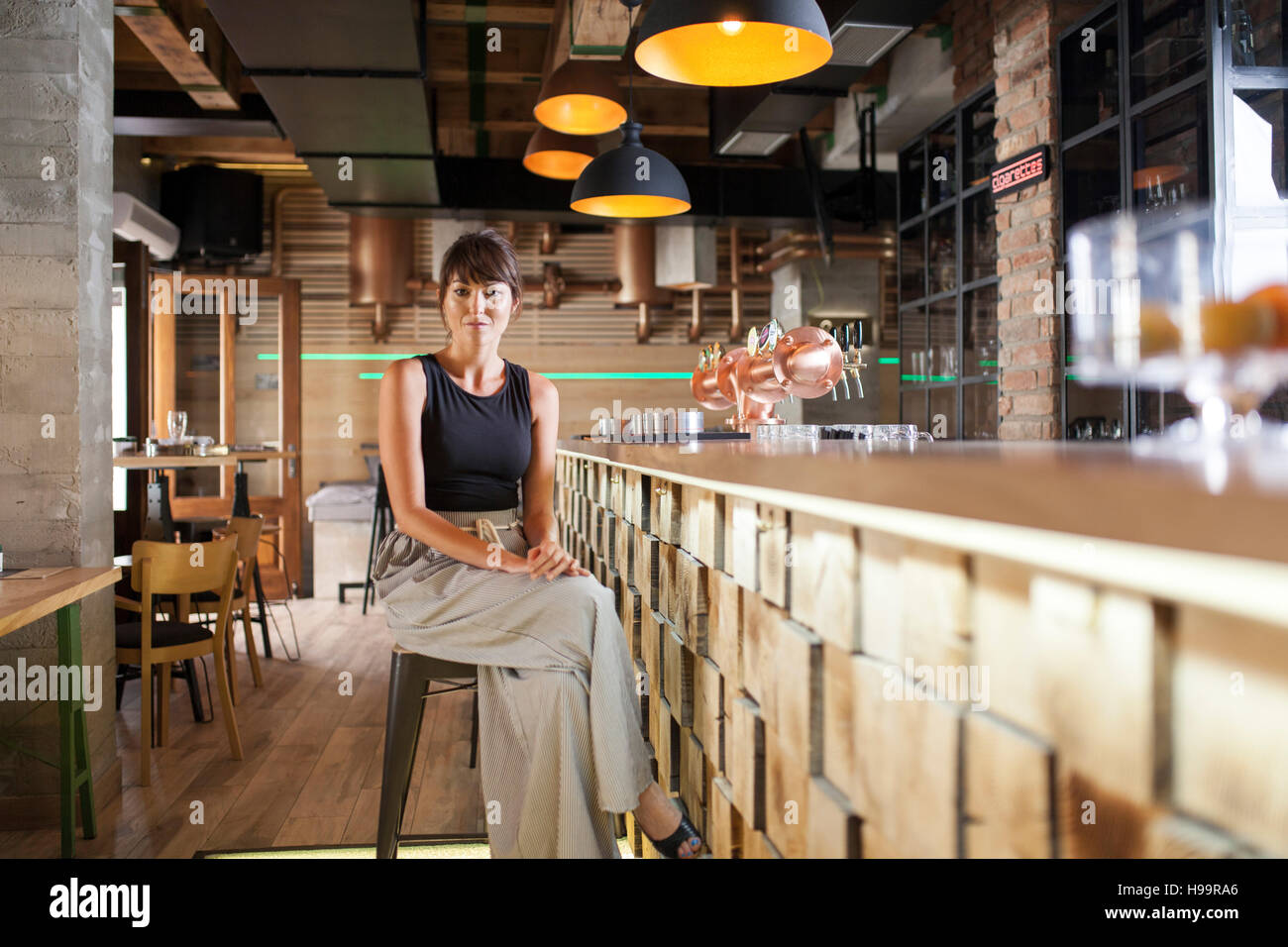 Mujer con pelo marrón sentado en el mostrador de bar en la cafetería. Foto de stock