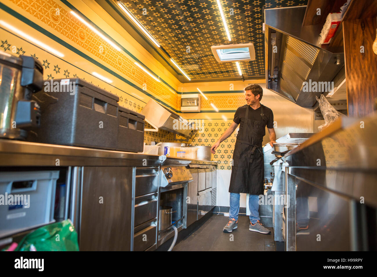 Empresario con delantal trabajando en cocina comercial en camión de alimentos Foto de stock
