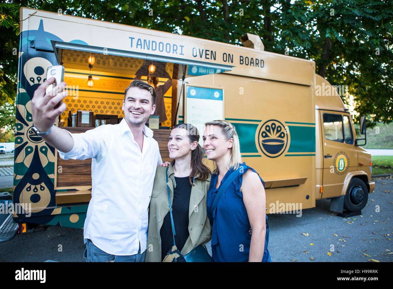 Los clientes teniendo un selfie junto al camión de alimentos Foto de stock
