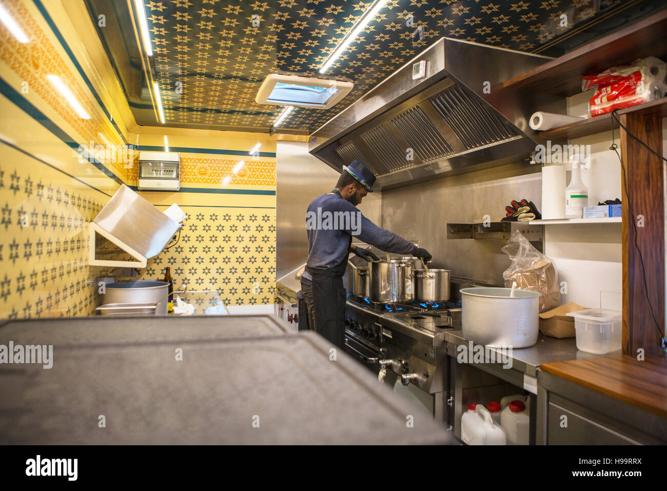 Hombre con sombrero cocinar en la cocina comercial de camión de alimentos Foto de stock