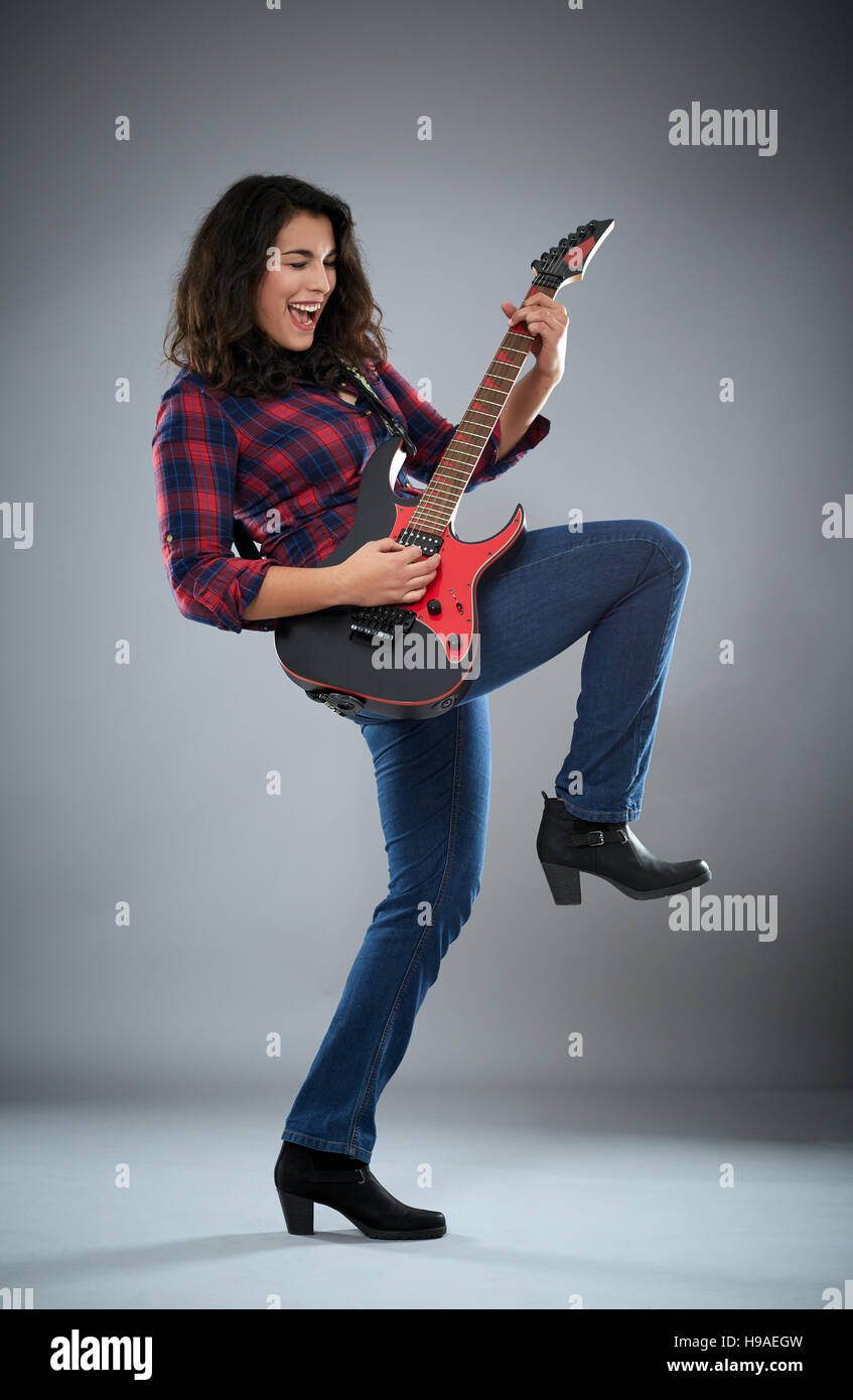 Chica hispana tocando la guitarra eléctrica, Foto de estudio sobre gris  Fotografía de stock - Alamy