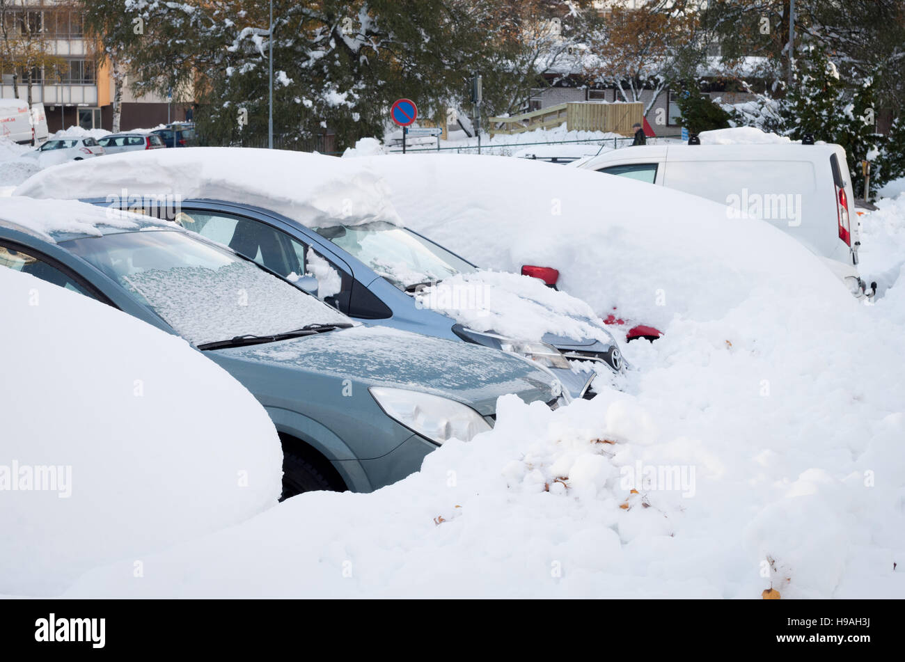 Los coches aparcados cubiertos de nieve después de una tormenta de nieve a principios de noviembre Foto de stock