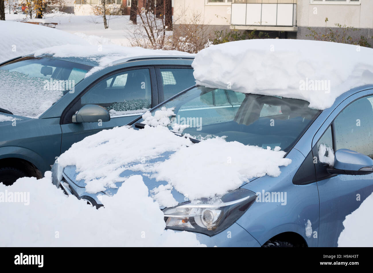 Los coches aparcados cubiertos de nieve después de una tormenta de nieve a principios de noviembre Foto de stock