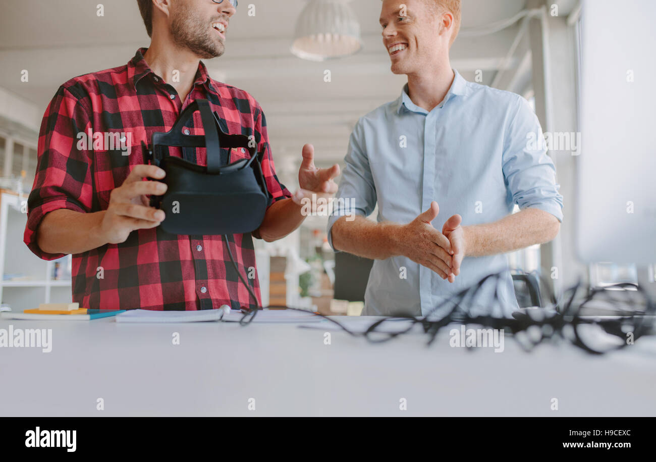 Captura recortada de dos jóvenes probando casco de realidad virtual. Los hombres de negocios y discutir las pruebas gafas de VR. Foto de stock