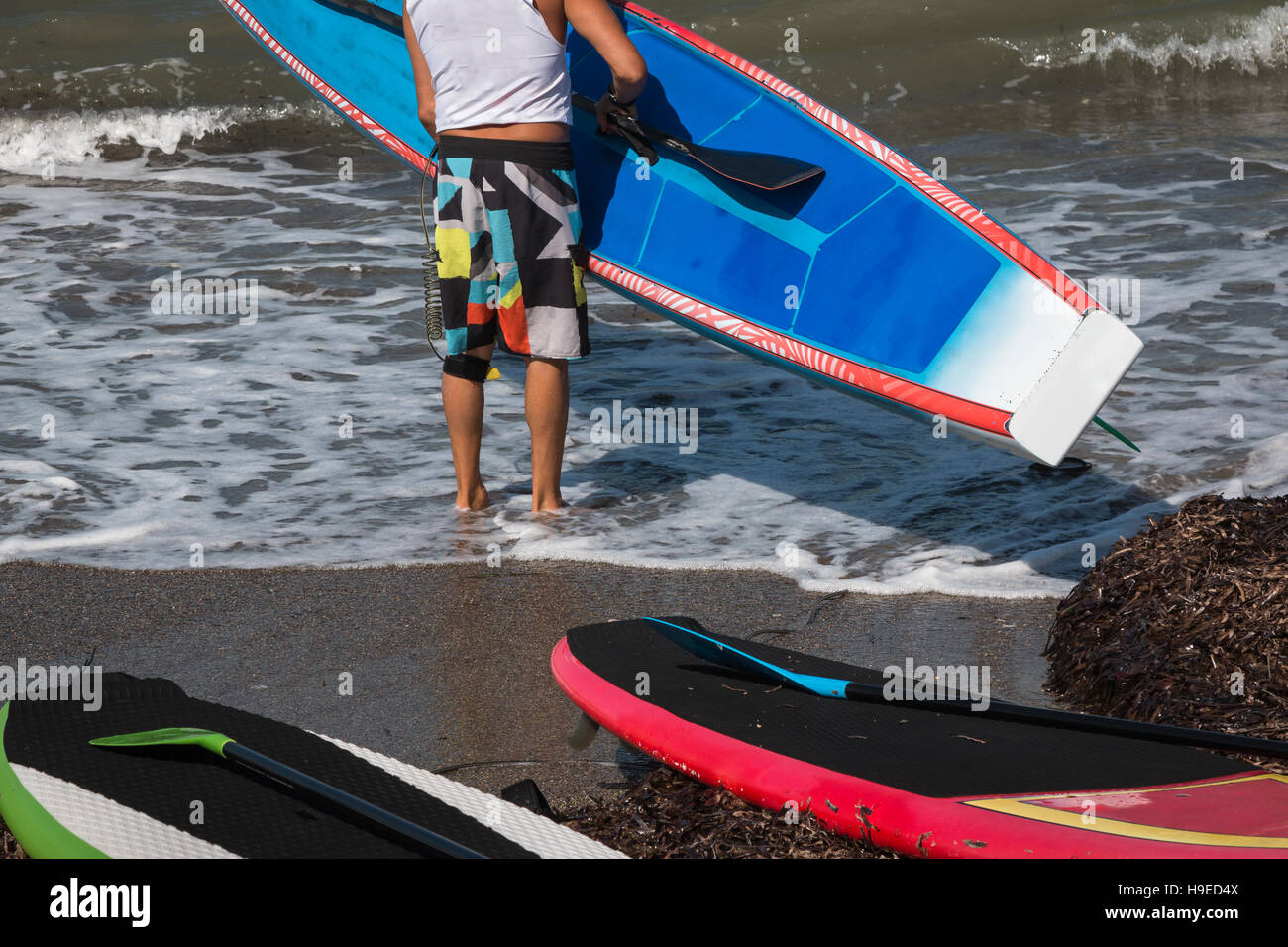 La Junta puso el hombre designado para Stand up surf en agua en Shoreline Foto de stock