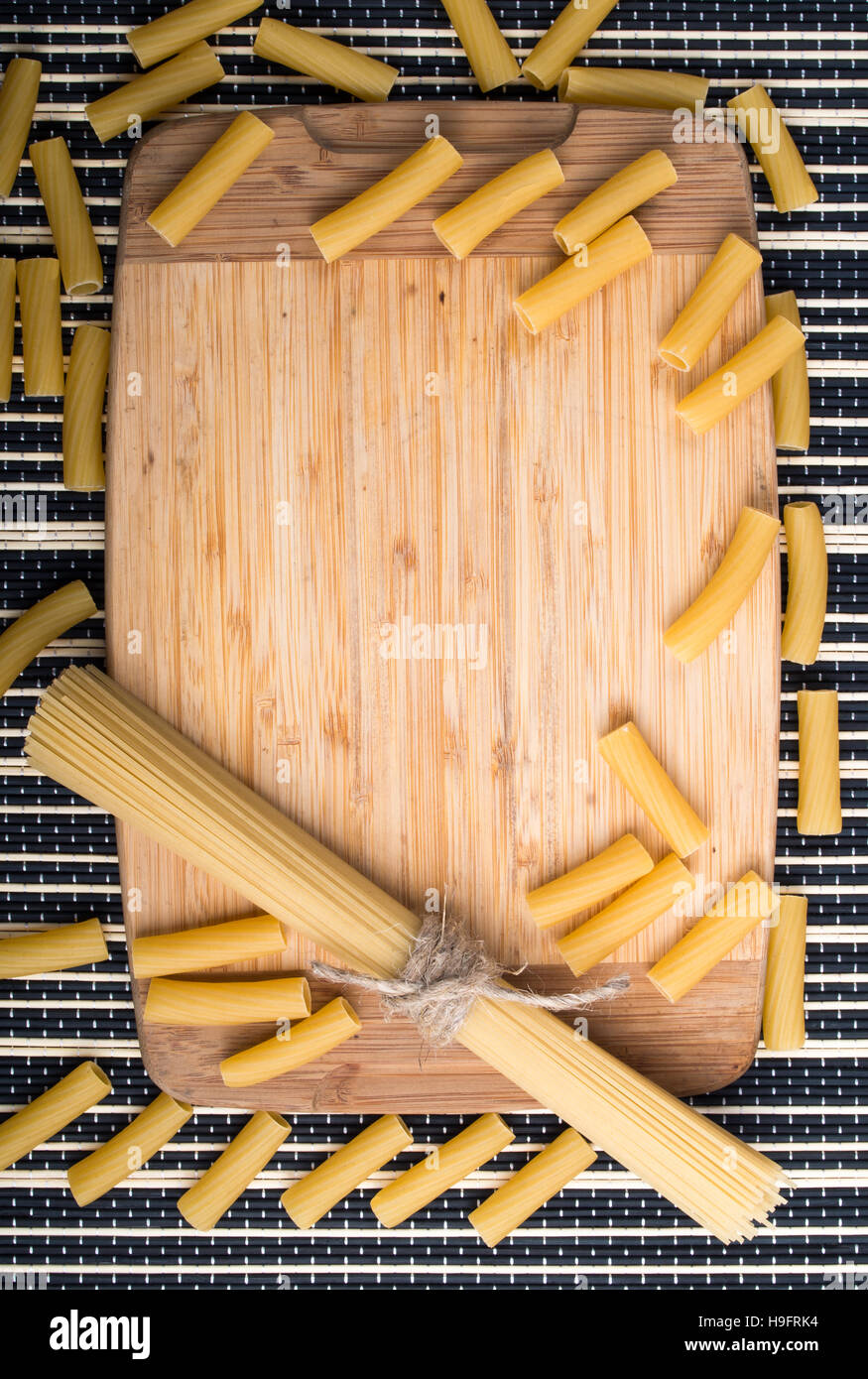 Fondo de alimentos con finos espaguetis y pasta en la mesa y la base de madera sobre un fondo rayado Foto de stock