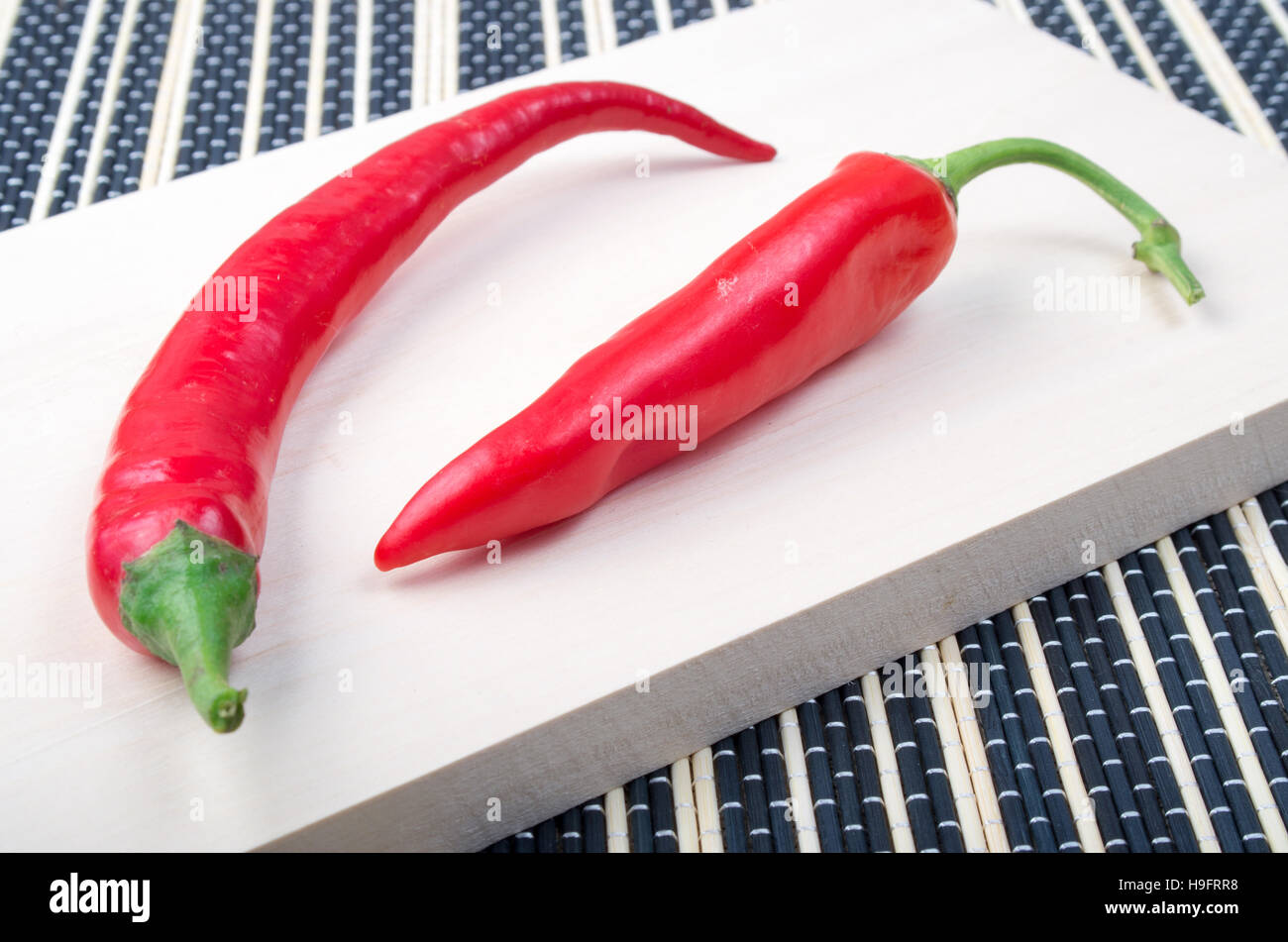 Dos red hot chili pepper closeup sobre un fondo claro de madera natural Foto de stock