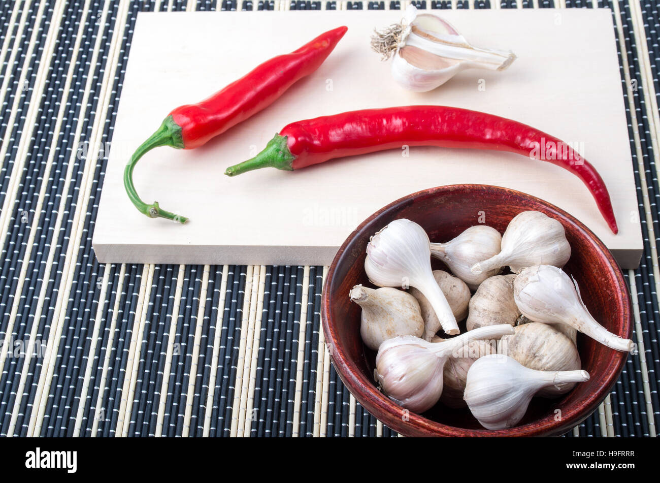 Fondo de especias para cocinar - Cayenne los chiles y el ajo en un tazón marrón sobre una mesa de cocina Foto de stock