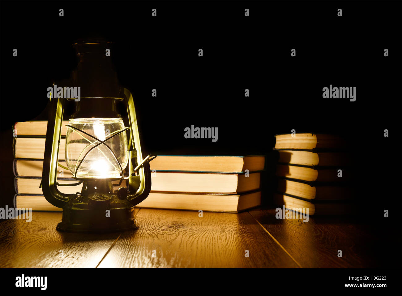 La luz de una lámpara de keroseno y libros sobre la mesa Foto de stock