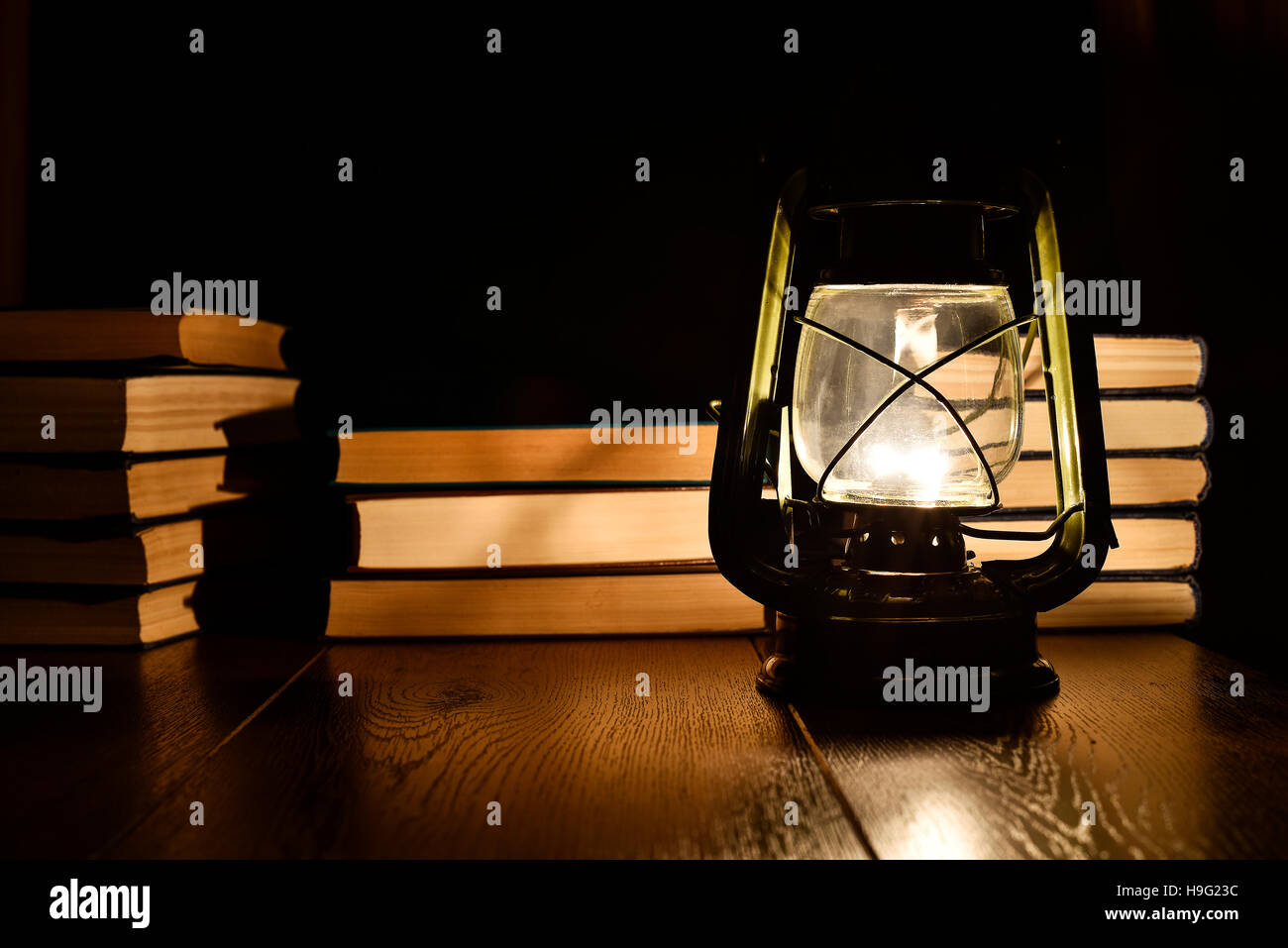 La luz de una lámpara de keroseno y libros sobre la mesa Foto de stock