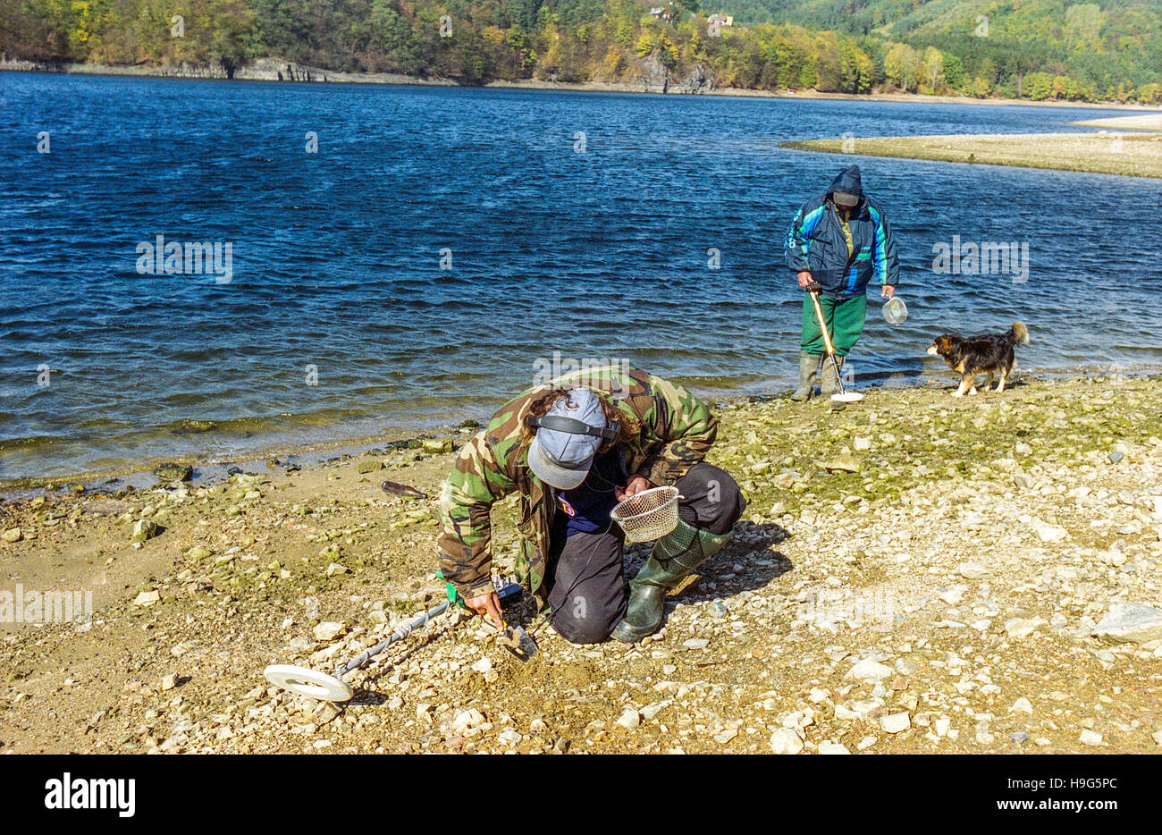 Los hombres con el detector de metales buscar elementos en la orilla de la presa de Orlik, República Checa Foto de stock