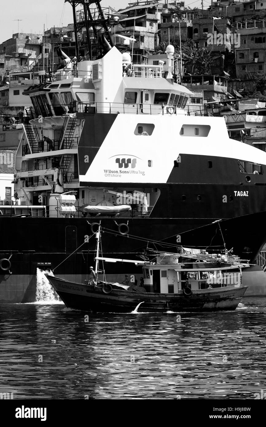 Barco pesquero pasando junto a los grandes buques de suministro de plataformas Foto de stock