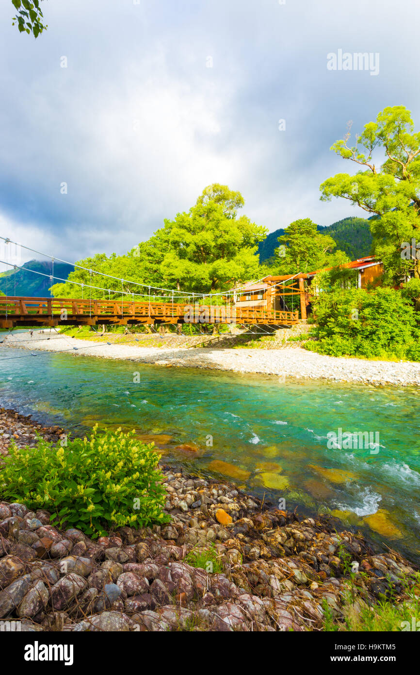 La luz de la mañana y las nubes dramático a través de Kappa Puente Bashi en las riberas de Azusa Gawa en el idílico pueblo de los Alpes Japoneses Foto de stock